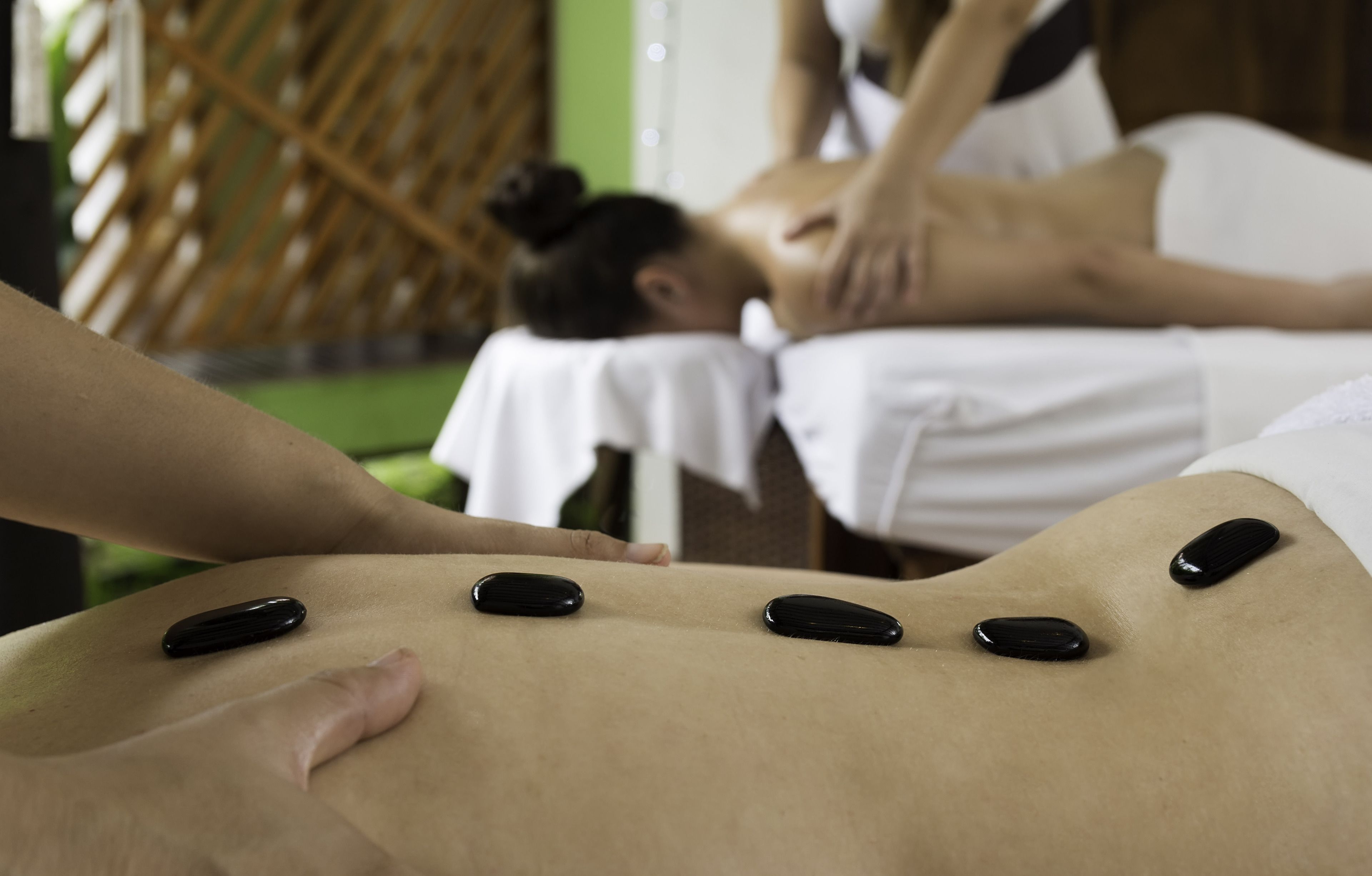 A massage therapy session with stones on a client's back.