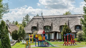 Ein Gebäude mit einem Strohdach und einem Spielplatz davor.