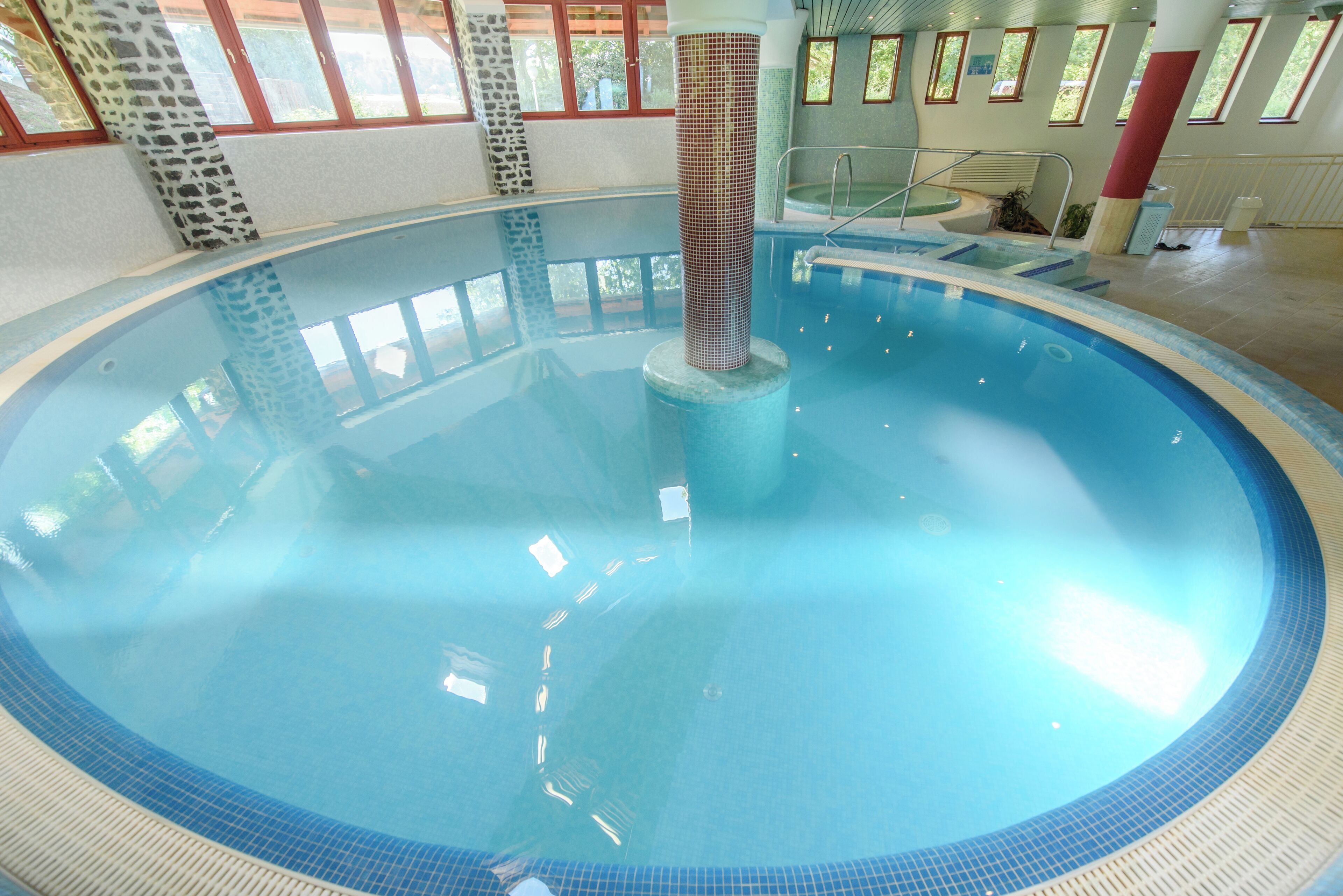 Une piscine intérieure dotée d’une colonne centrale, d’une eau claire et d’un sol carrelé.