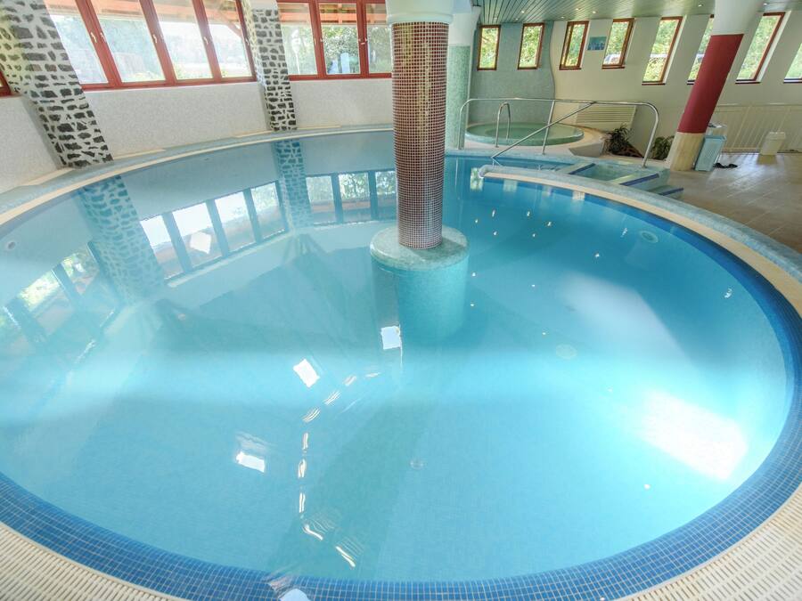 Una piscina interior con una columna central, agua cristalina y suelo de baldosas.