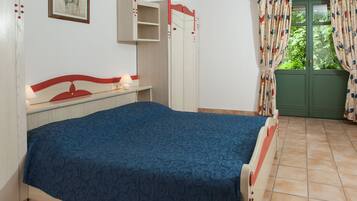 A bedroom with a bed, a wardrobe, a desk, and a window with curtains.