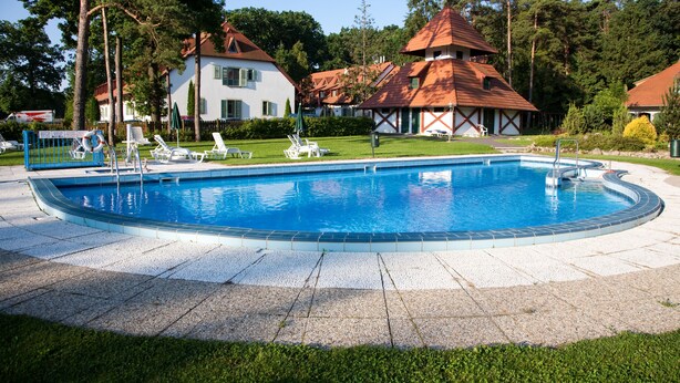 Ein Schwimmbad mit Liegestühlen und einem kleinen Gebäude mit rotem Dach.