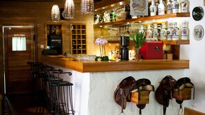 Eine Bar mit Hockern, einer Kaffeemaschine und Ausrüstung für das Reiten an der Wand.