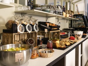 Ein reichhaltiges Buffet mit verschiedenen Speisen, darunter Obst, Gebäck und Soßen.