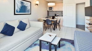 A modern living room with a sofa, a small table, and a dining area with chairs. - Aparthotel Adagio Monaco Monte Cristo (Beausoleil)