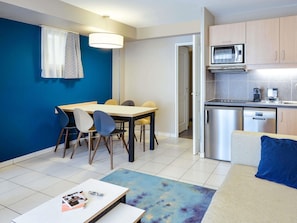 Um espaço compacto com área de refeições, cozinha compacta e sofá com almofada azul.