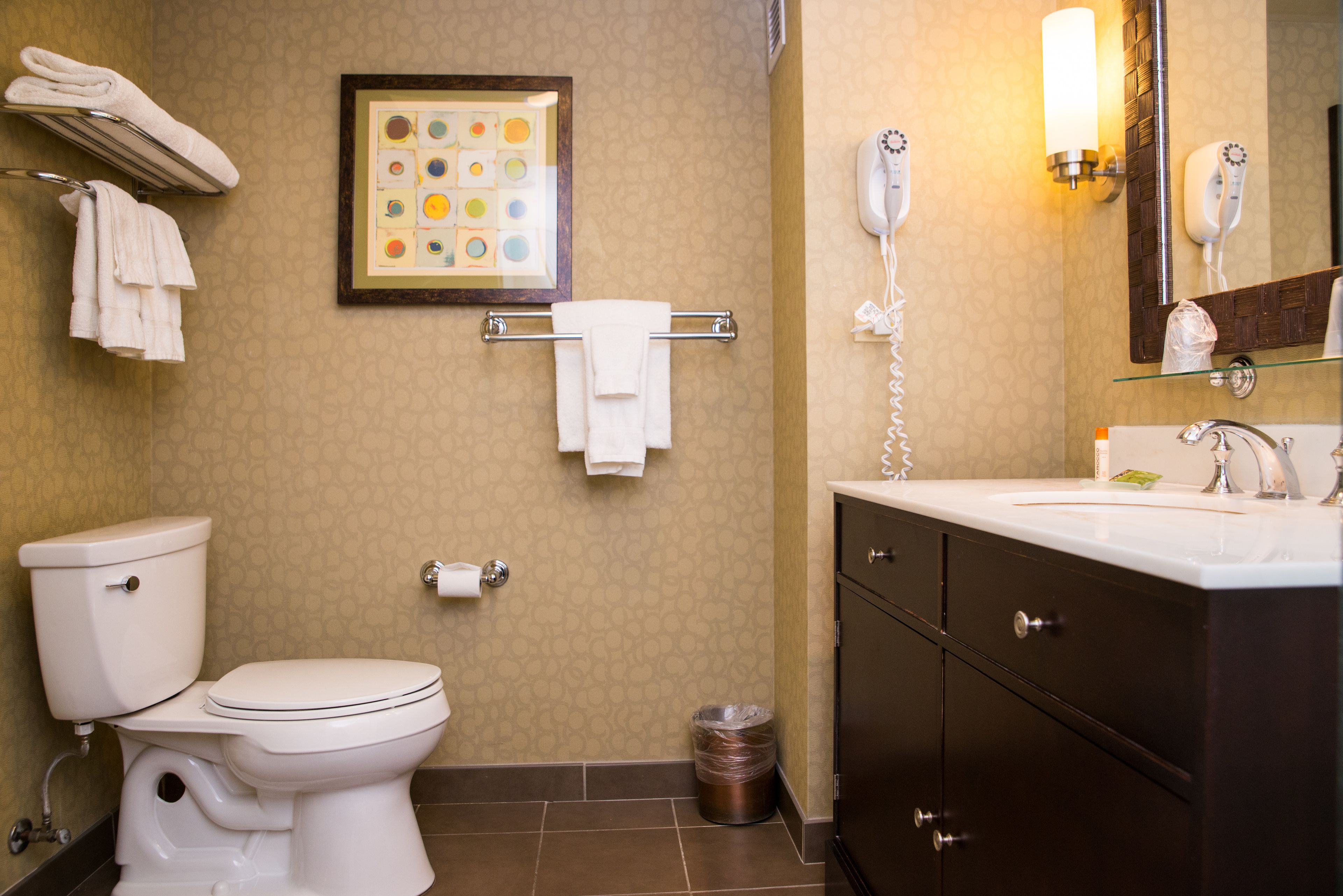 Une salle de bain comprenant des toilettes, un lavabo, un meuble-lavabo, un porte-serviettes et un tableau encadré au mur.