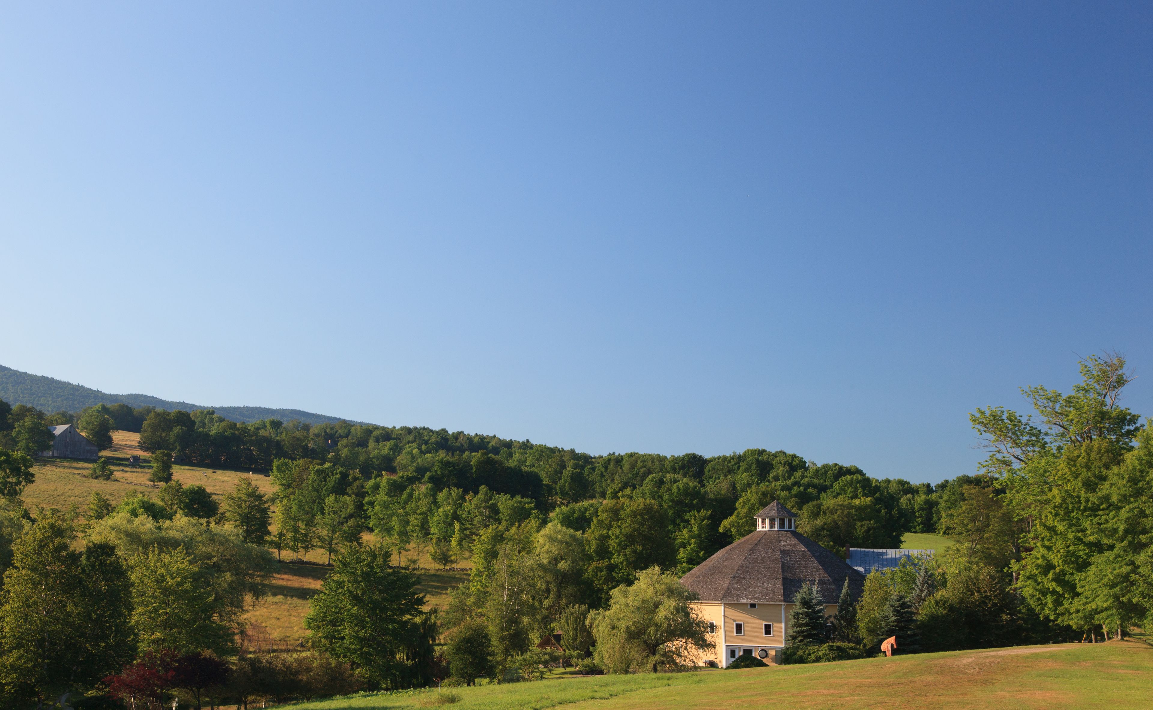 A rural landscape with a large house surrounded by trees and open fields.