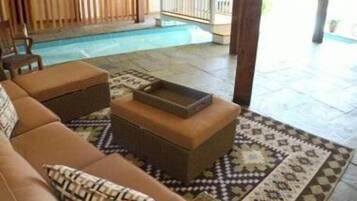 Relax by the pool in a spacious area with a comfortable seating area and wooden deck.