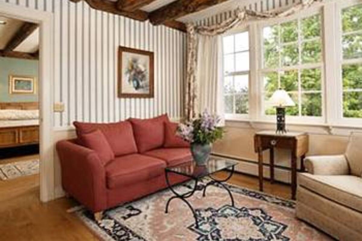 A cozy living room with a red sofa, a patterned rug, and a window with curtains.