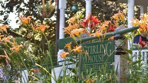 A sign for 'Stirling House Bed & Breakfast' surrounded by vibrant flowers.