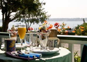 A table set with a glass of orange juice, a glass of white wine, and a dessert with whipped cream and berries. - Stirling House Bed & Breakfast (Greenport)