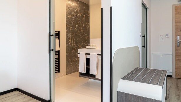 A modern bathroom with a glass door, a white sink, and a towel rack. - CHRIZZ Rooms (Graz)