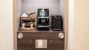 A compact coffee station with a coffee machine, a coffee grinder, and a shelf with coffee pods. - CHRIZZ Rooms (Graz)