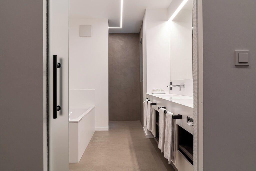 Un baño moderno con un espejo grande, una bañera y un lavamanos.