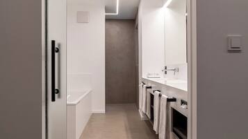 Un baño moderno con un espejo grande, una bañera y un lavamanos.