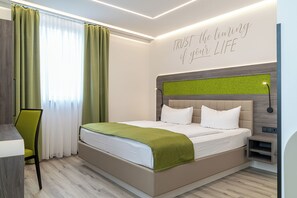 Ein modernes Hotelzimmer mit einem Bett, einem Schreibtisch und einem grünen Stuhl.