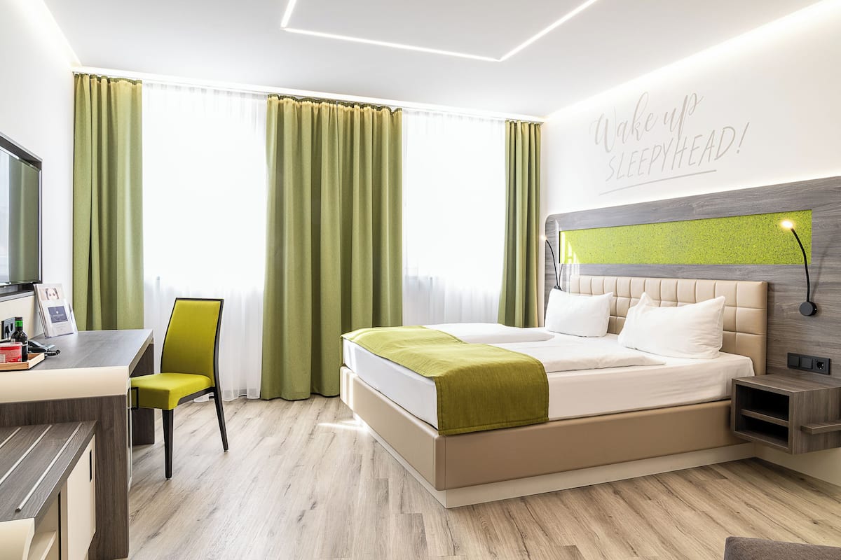 Ein modernes Hotelzimmer mit Bett, Schreibtisch und Stuhl.