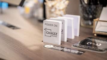 Ein Empfangsschalter mit einem Schild, auf dem 'POWER ON CHRIZZ' steht, und einem Kartenhalter mit mehreren Karten.