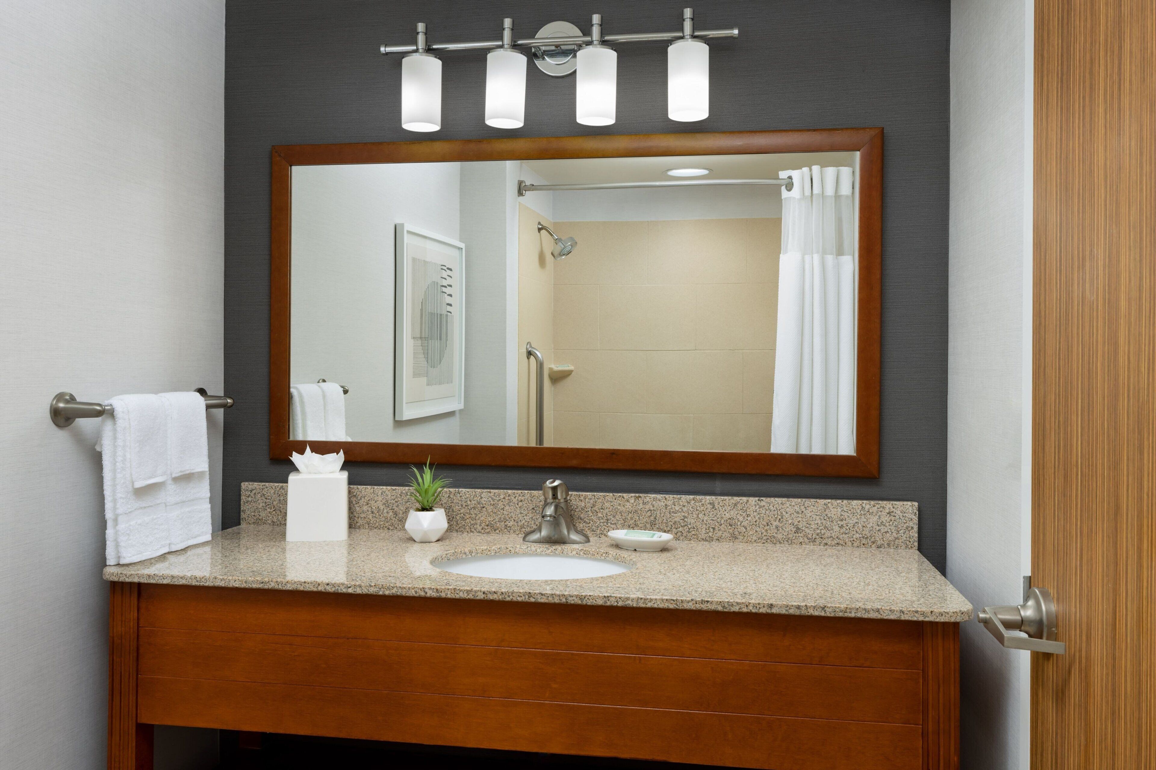 A bathroom with a wooden vanity, a large mirror, and a shower curtain.