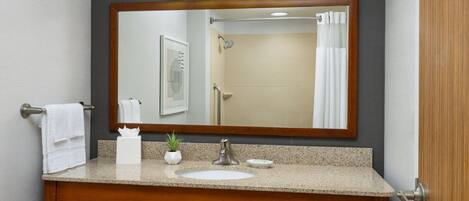 A bathroom with a wooden vanity, a large mirror, and a shower curtain.
