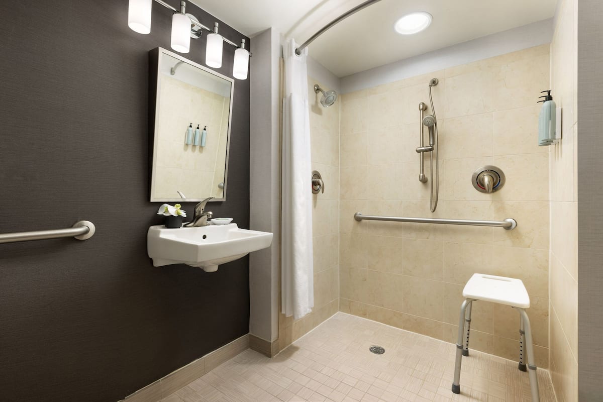 Ein modernes Badezimmer mit Dusche, Waschbecken und Spiegel.