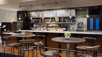 Un bar moderno con varias opciones de asientos, una barra con menú y diferentes utensilios y botellas.