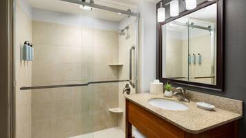 A modern bathroom with a glass-enclosed shower, a vanity with a sink, and a large mirror.