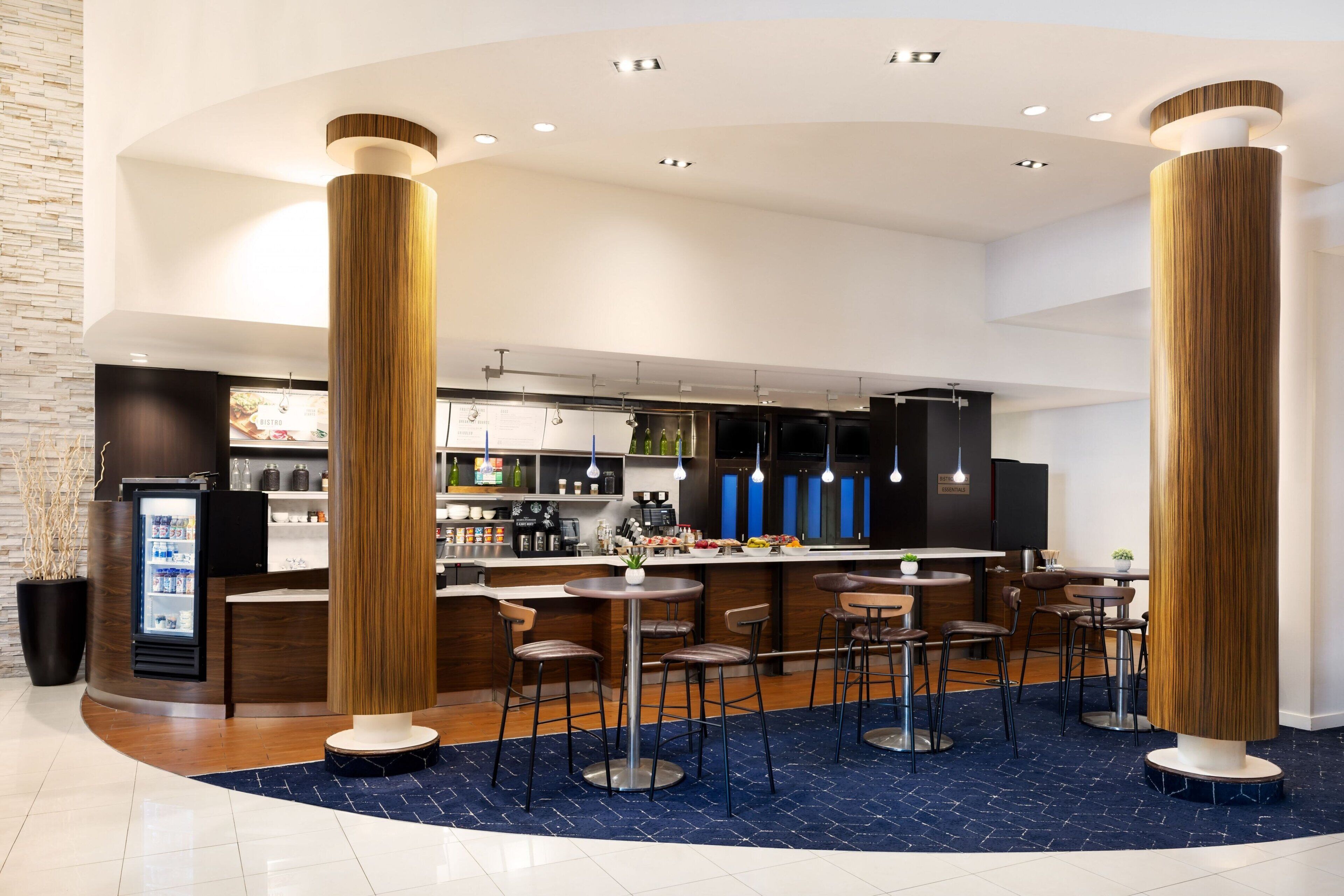 A modern bar area with high stools, a central bar counter, and a kitchen in the background.