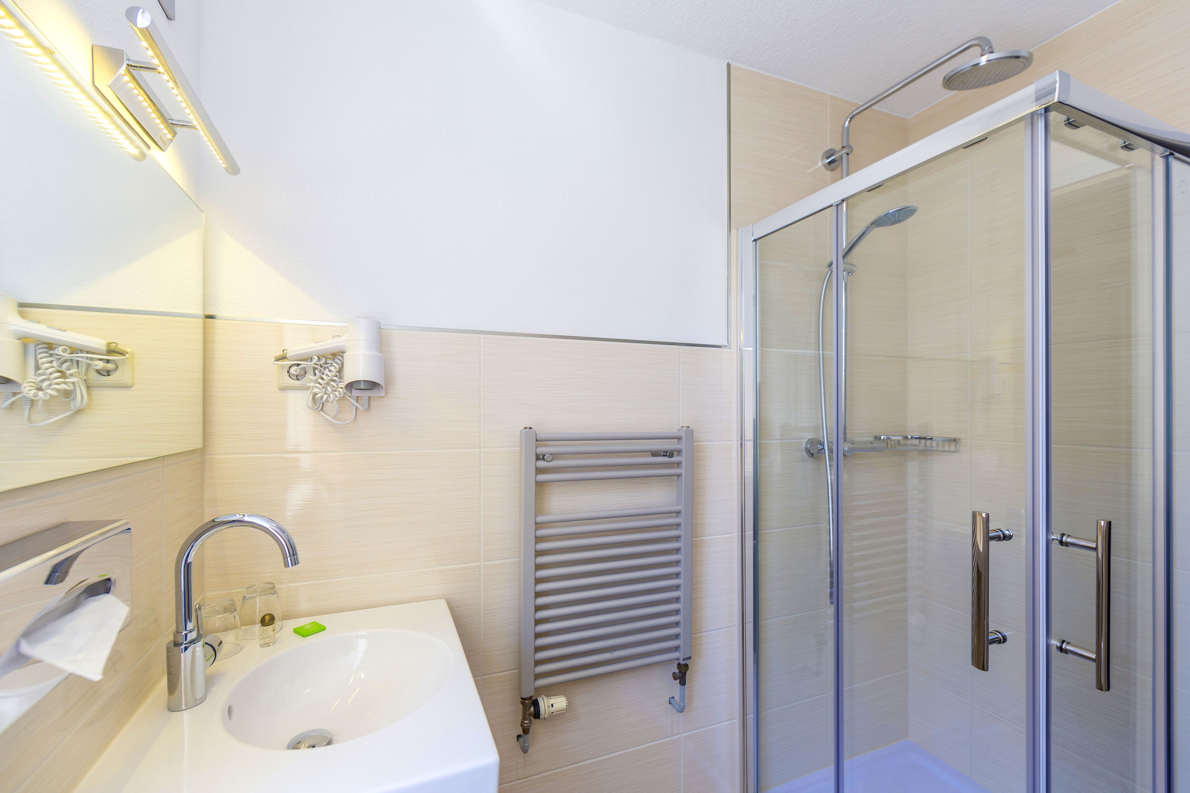 Een moderne badkamer met een wastafel, spiegel, handdoekhouder en douchecabine.