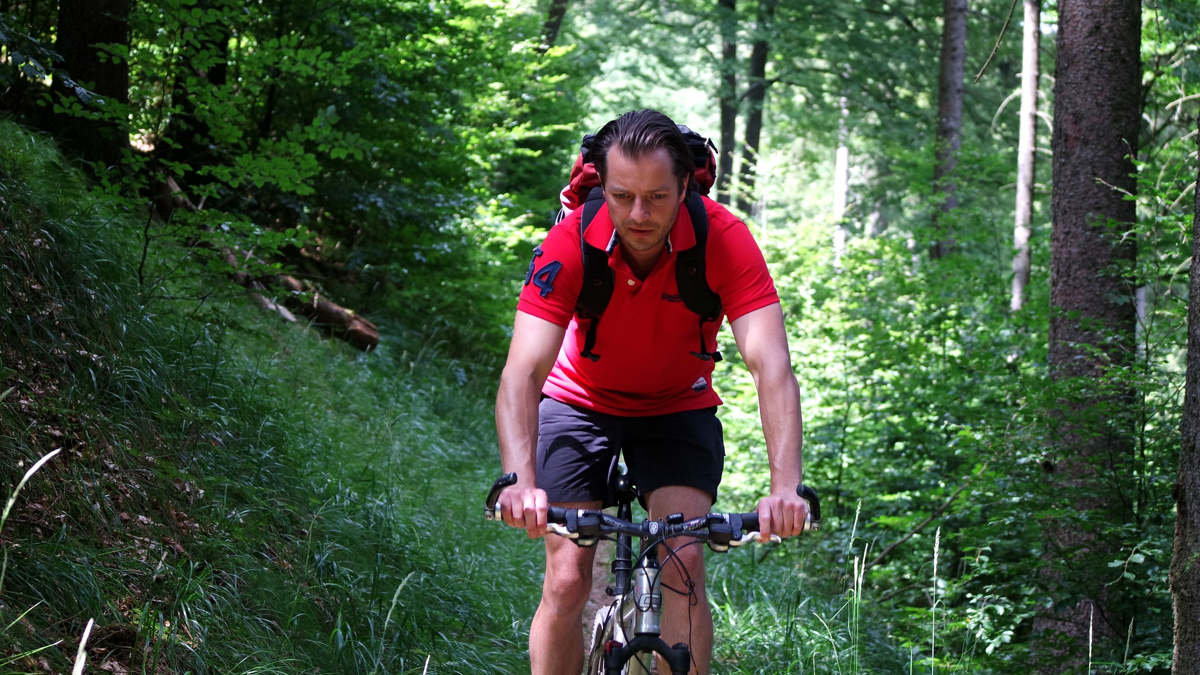 A person riding a bicycle in a forested area.