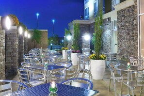 An outdoor patio with multiple tables and chairs, surrounded by stone walls and potted plants. - Holiday Inn Southaven Central - Memphis by IHG (Southaven)