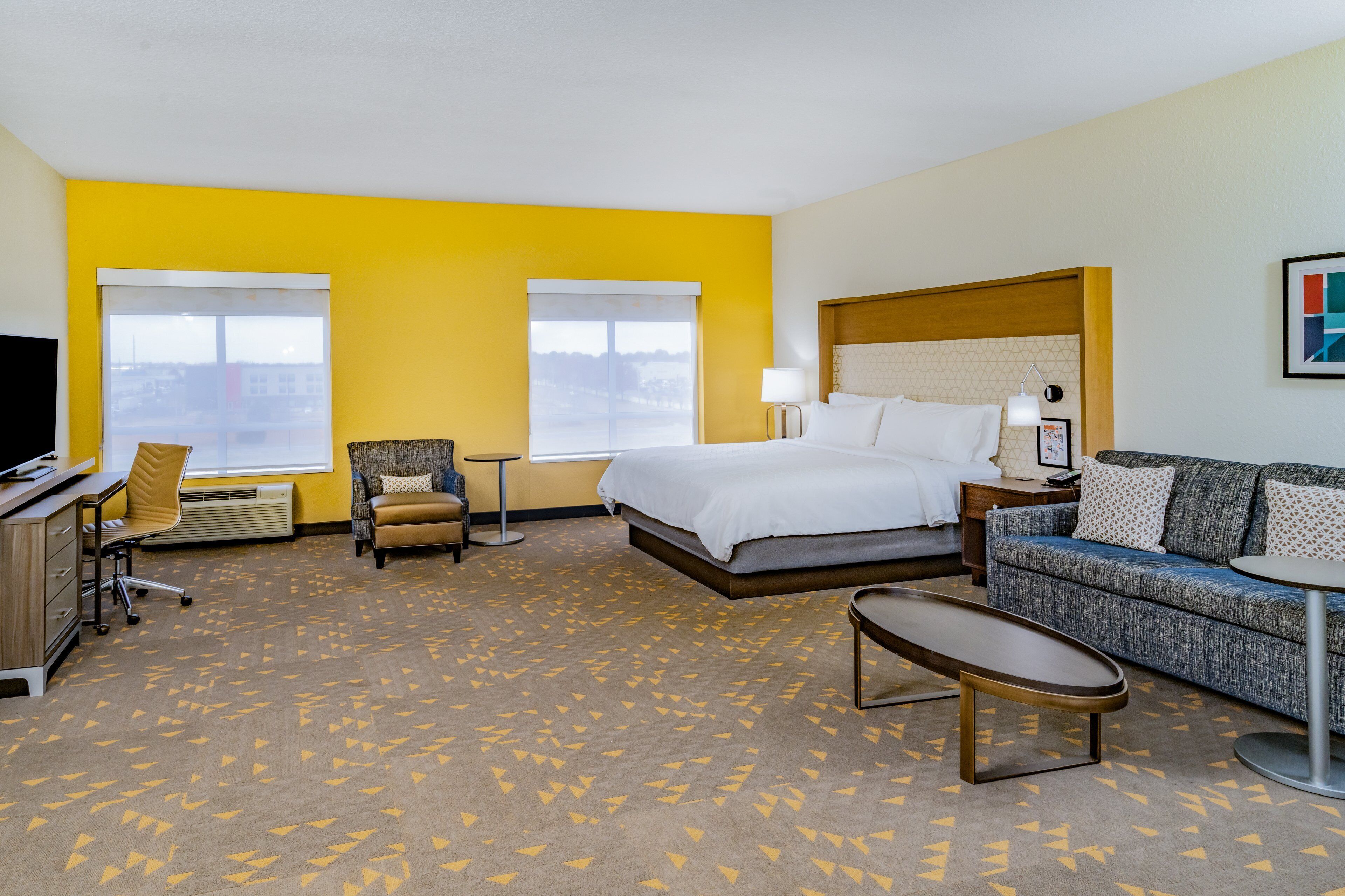 A hotel room with a bed, a sofa, a desk, and two chairs.