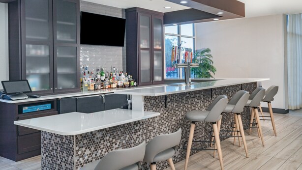 A modern kitchen with a bar area, including a countertop with bar stools and a laptop. - Holiday Inn Southaven Central - Memphis by IHG (Southaven)
