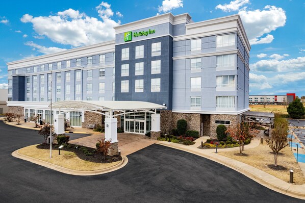 A Holiday Inn hotel with a modern design, featuring a covered entrance, a parking lot, and landscaped areas. - Holiday Inn Southaven Central - Memphis by IHG (Southaven)