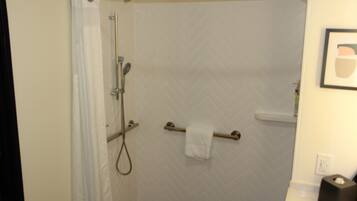 A bathroom with a shower, a towel rack, and a toilet paper holder.