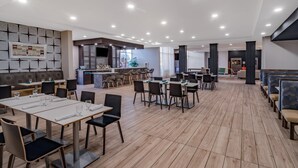 A spacious dining area with multiple tables and chairs, a bar area, and a seating section with cushioned benches. - Holiday Inn Southaven Central - Memphis by IHG (Southaven)