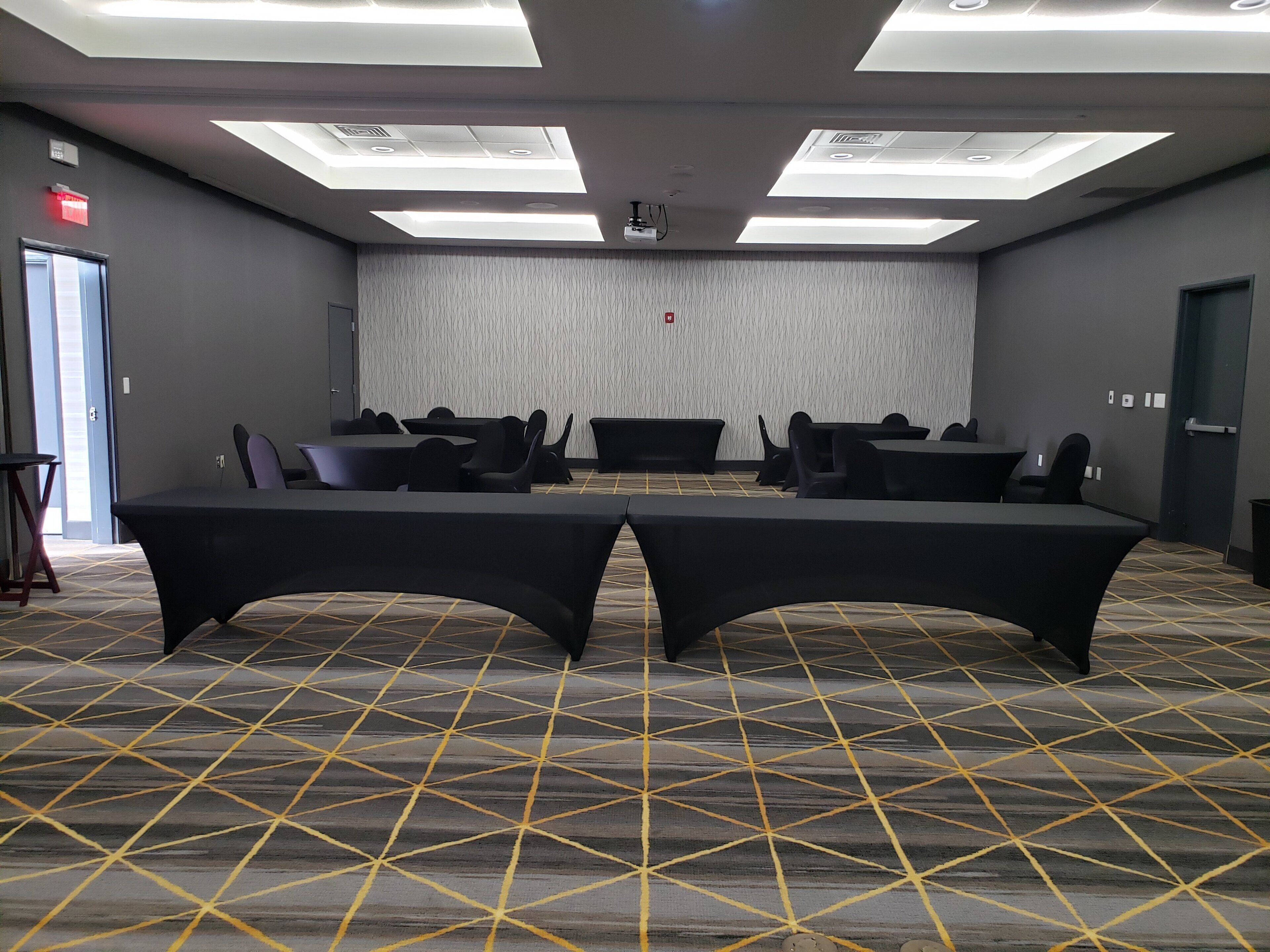 A conference room with tables and chairs, a patterned carpet, and ceiling lights.