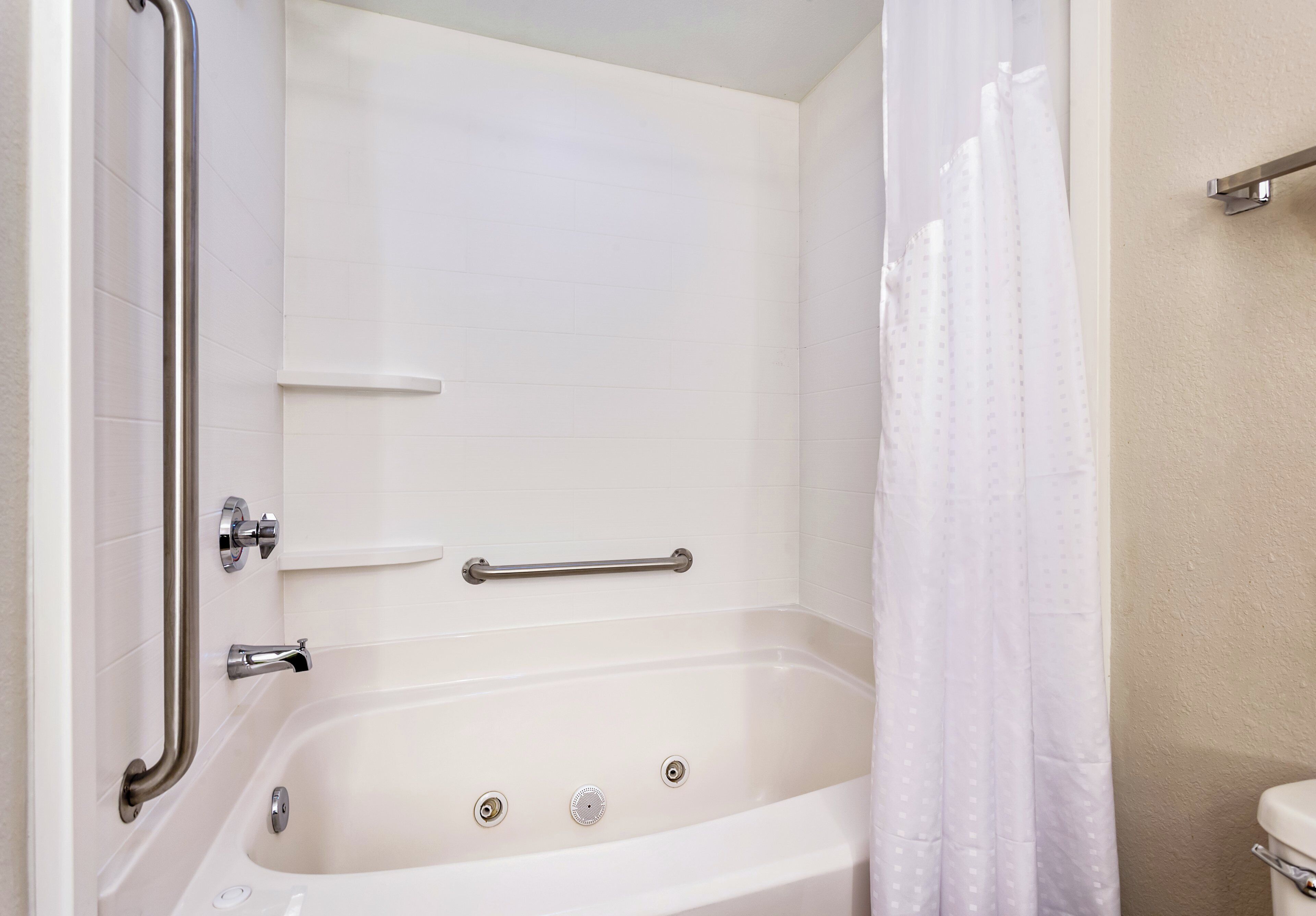 Een badkamer met een bad, douchegordijn en toilet.