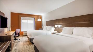 A hotel room with two beds, a desk with a chair, a television, and a large window.