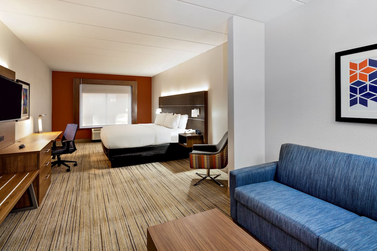 Une chambre d’hôtel équipée d’un lit, d’un bureau, d’une chaise, d’un canapé et d’une télévision.