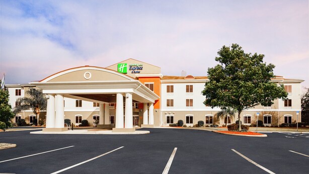 A Holiday Inn Express & Suites with a central entrance, parking lot, and surrounding greenery. - Holiday Inn Express Hotel & Suites Inverness by IHG (Lecanto)