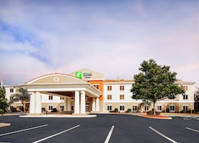 Un Holiday Inn Express & Suites con entrada principal, estacionamiento y zonas verdes circundantes.