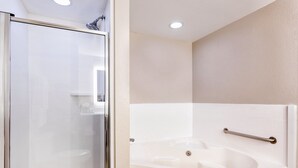 A modern bathroom with a glass shower enclosure, a white bathtub with a grab bar, and recessed ceiling lighting. - Holiday Inn Express Hotel & Suites Inverness by IHG (Lecanto)