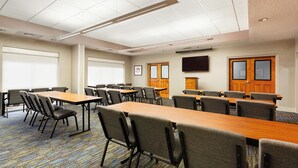 A conference room with tables and chairs, a flat-screen TV, and a patterned carpet. - Holiday Inn Express Hotel & Suites Inverness by IHG (Lecanto)