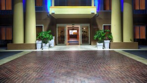 A hotel entrance with a brick-paved driveway, large columns, and potted plants. - Holiday Inn Express Hotel & Suites Inverness by IHG (Lecanto)