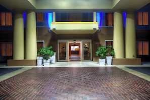 A hotel entrance with a brick-paved driveway, large columns, and potted plants. - Holiday Inn Express Hotel & Suites Inverness by IHG (Lecanto)