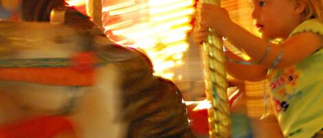 A carousel with a child holding onto a pole.