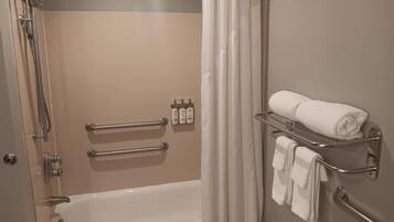 A bathroom with a bathtub, a shower, and a towel rack with towels.