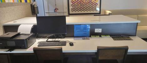 A reception desk with a computer, printer, and chairs.